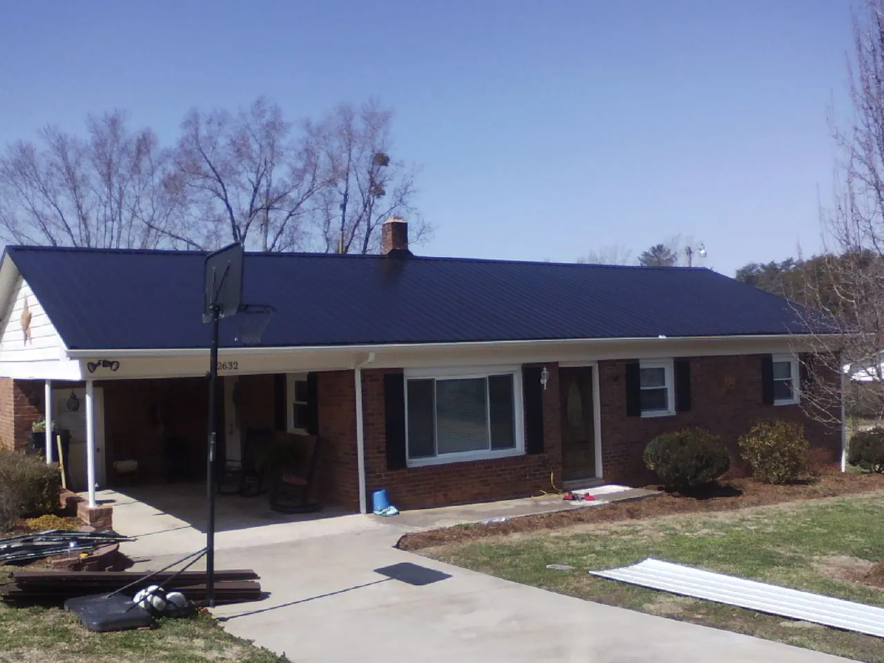 Finished dark blue metal roof on a brick ranch with a carport in New Berlinville