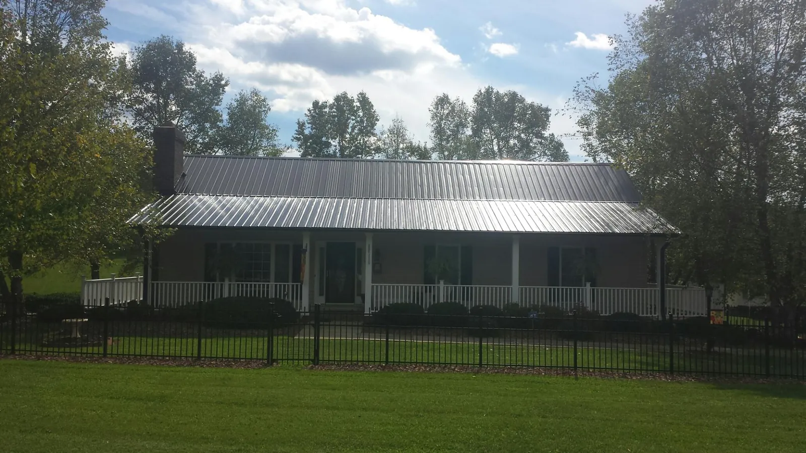 Gray metal roof on a brick ranch with a full width front porch — Gutter Guard Installation work by our crew in New Berlinville