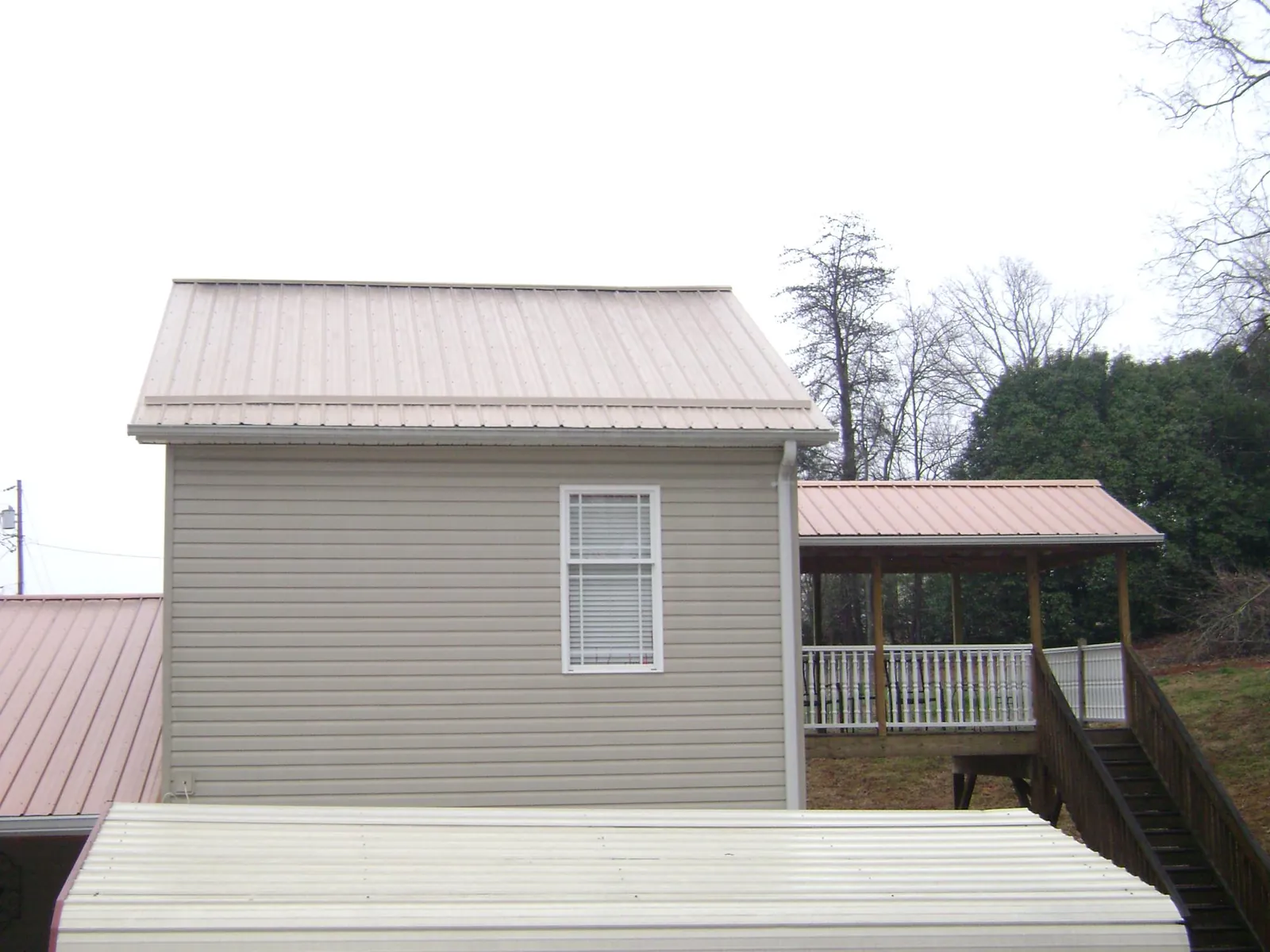 Tan metal roofs on a two story addition and attached porch, from a Roof Replacement job in New Berlinville