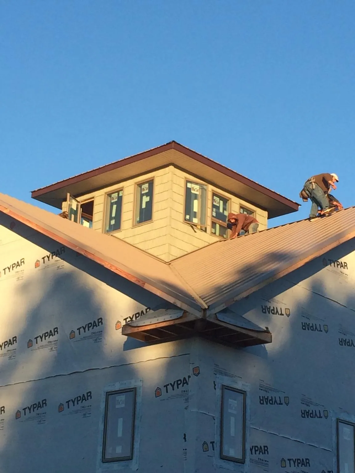 Roofers working around a rooftop cupola on a new metal roof at sunset — Roof Waterproofing in New Berlinville by Roofing Brothers